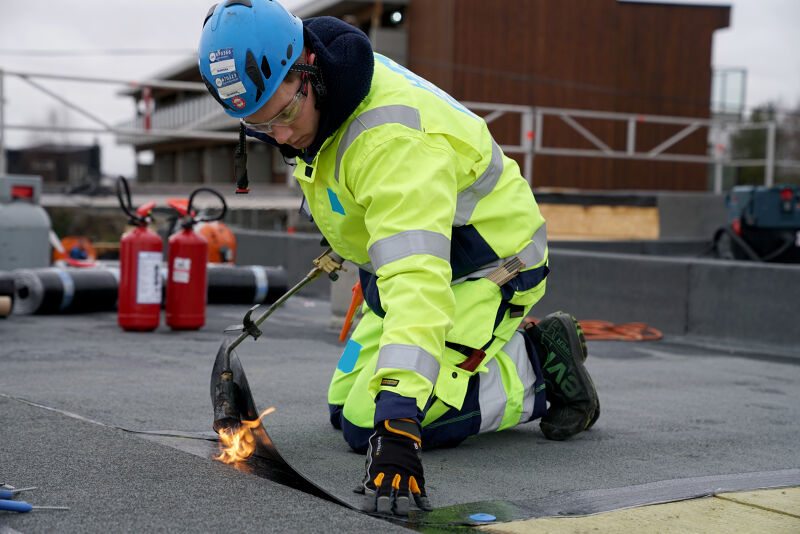 Arbeider legger tak på bygg